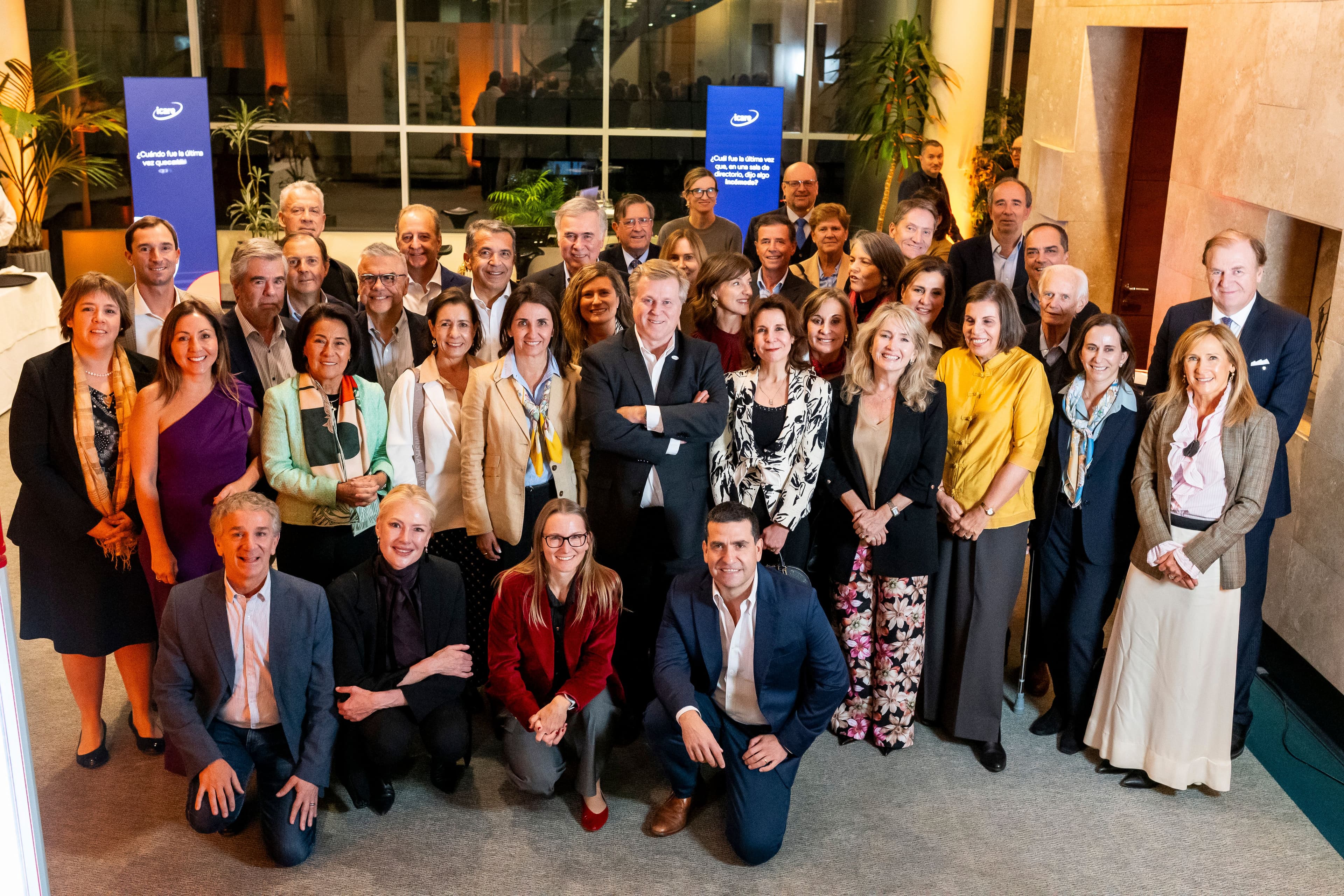 A large group of diverse professionals, some standing and some kneeling, at an indoor event.