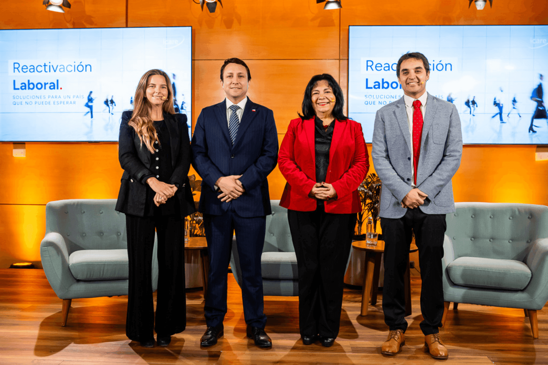 Four professionals stand before screens displaying 'Reactivación Laboral' in a formal setting.