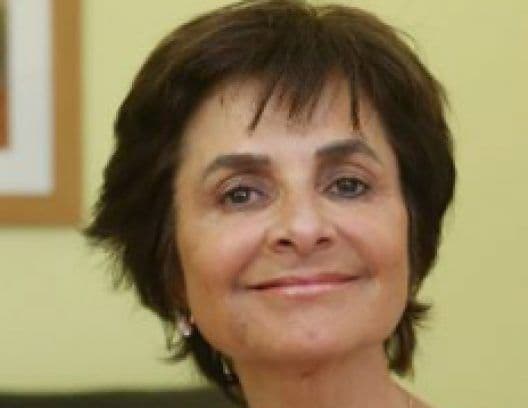 Older woman with short dark hair and dark eyes, smiling gently at the camera.